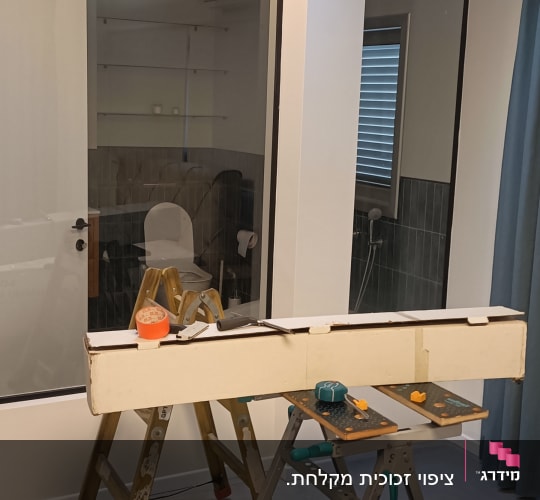 סולם, שולחן עבודה, קרטון וכלי עבודה בחדר